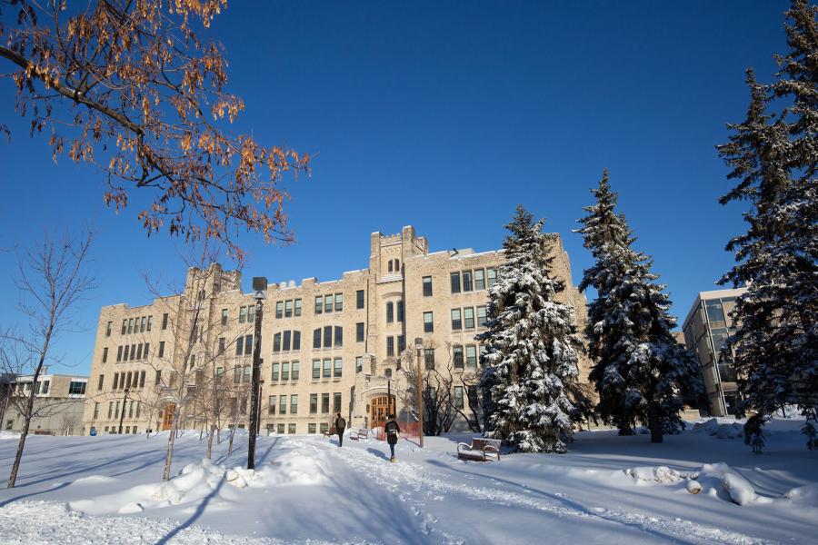 Students walk path on Fort Garry campus in winter, near Buller Building.