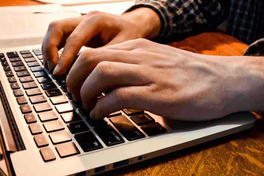 A close up shot of hands typing on a laptop.