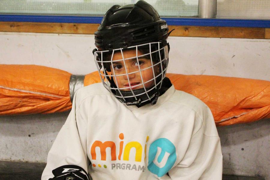 A little girl wearing hockey equipment.