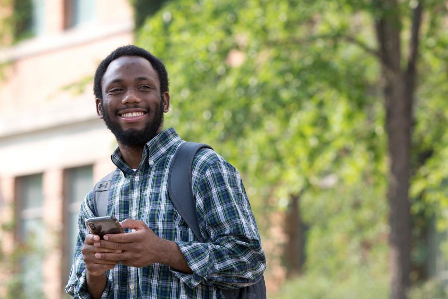 Student smiling beside his bike on campus. 