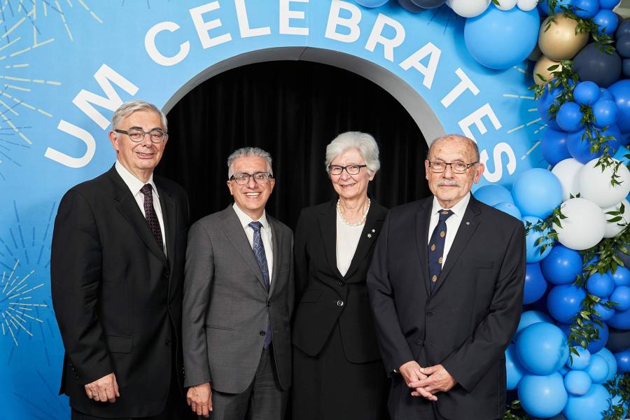 President Benarroch stands with past presidents under a blue arch reading U M celebrates, and balloons. 