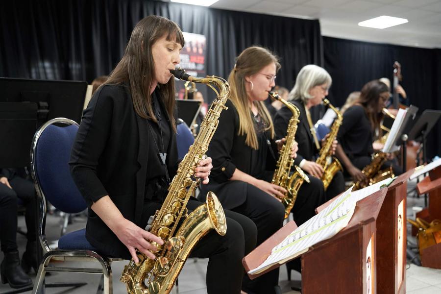 Four women playing saxaphones within a larger ensemble.