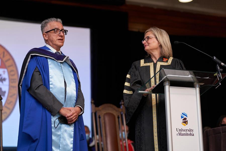 President Benarroch stands on stage at a podium beside Chancellor Mahon.