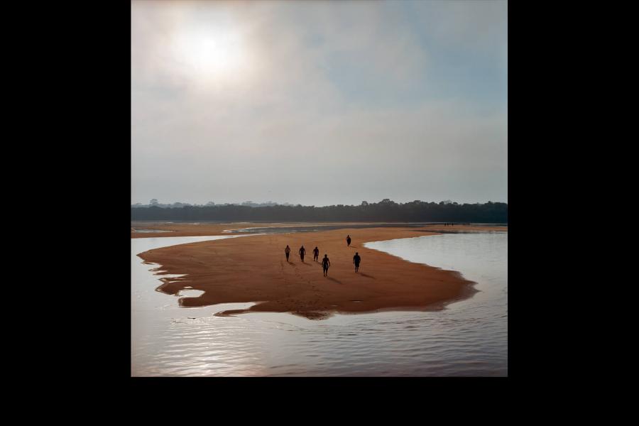 People walk on sand surrounded by water. Photo by Aaron Vincent Elkaim [BA/03]