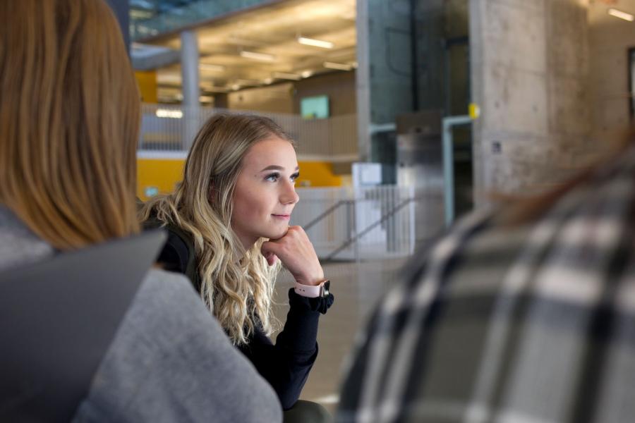 A close up of a UM student with their hand under their chin, thinking while looking off into the distance.