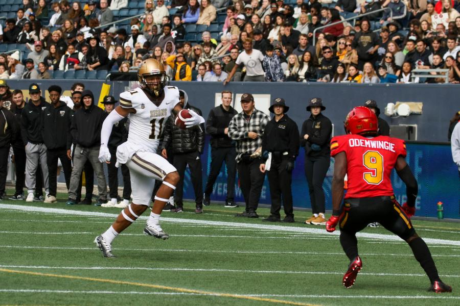 An image of a Bisons football athlete running and holding a football.