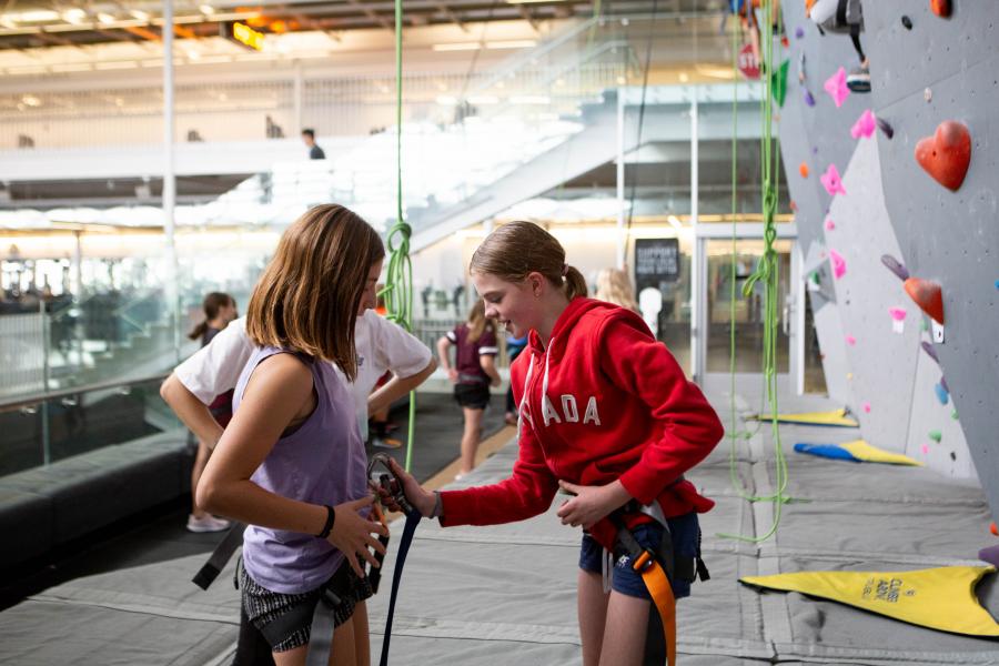 An image of two Mini U students getting suited up to rock climb.