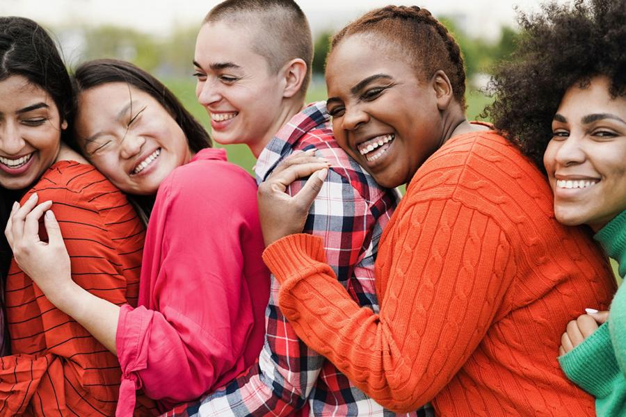 Five young people of all body types posing together, smiling.