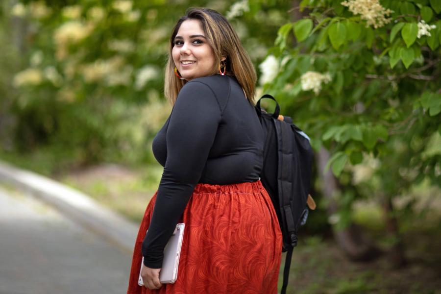 A University of Manitoba student smiles as she looks over her shoulder while walking outdoors at the Fort Garry campus.