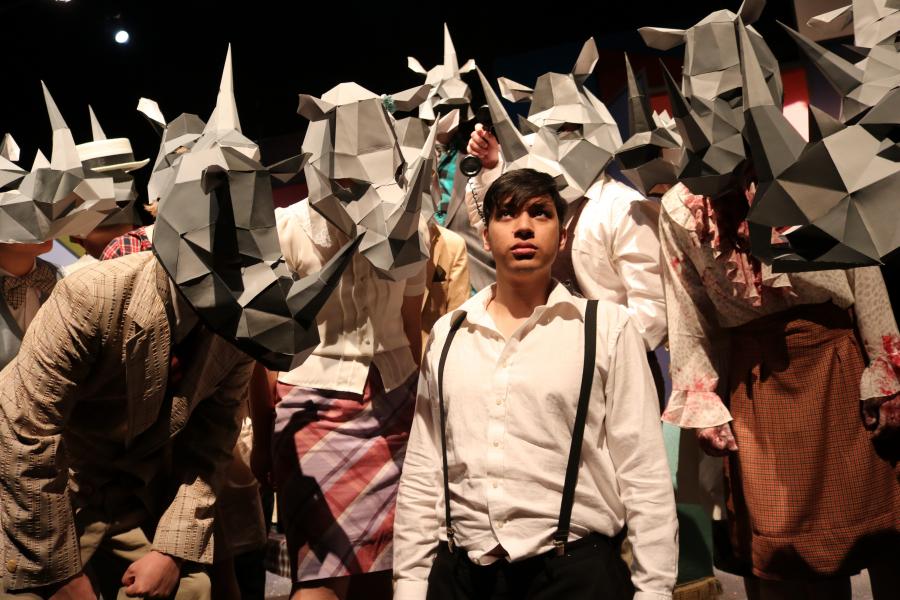 Man surrounded by a group of people wearing Rhinoceros masks.