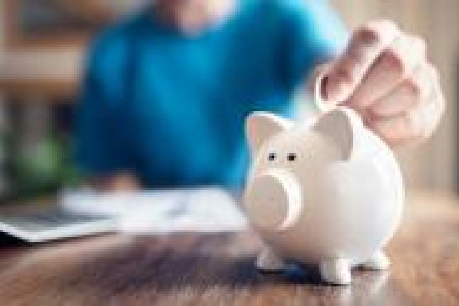 Person putting a coin into a piggy bank.