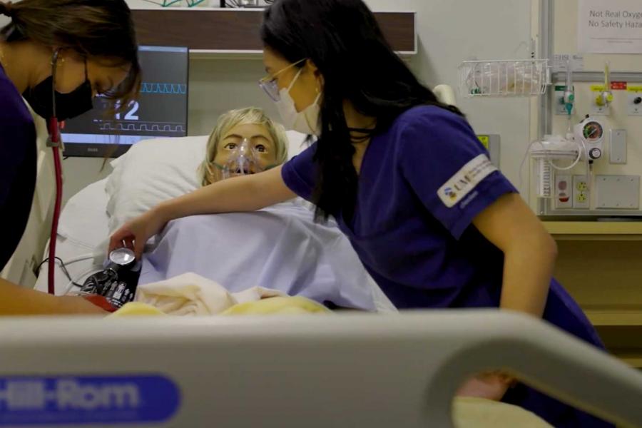 Two UM nursing students working on a patient.