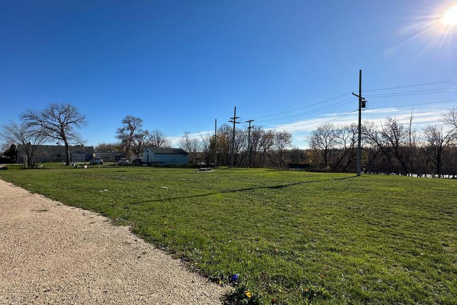 The future site of the Garden for Wellbeing on the Fort Garry Campus in summer. The sun shines on a green field area.