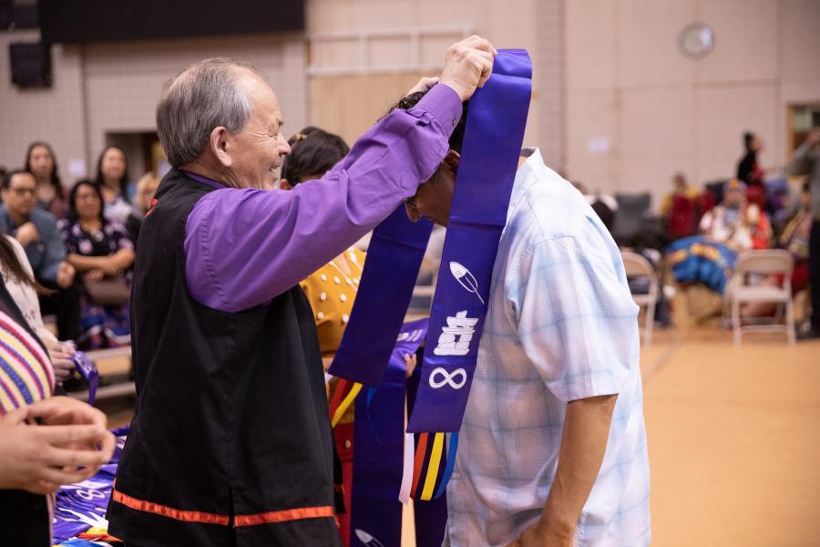 An indigenous graduation stole being placed on a graduand during the annual traditional pow wow.