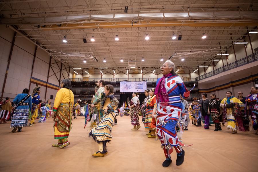 Indigenous dancers in traditional dress dancing at the annual traditional graduation pow wow.