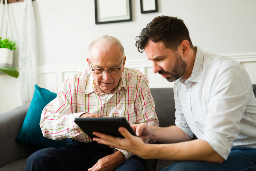 a senior and middle-aged man reading together