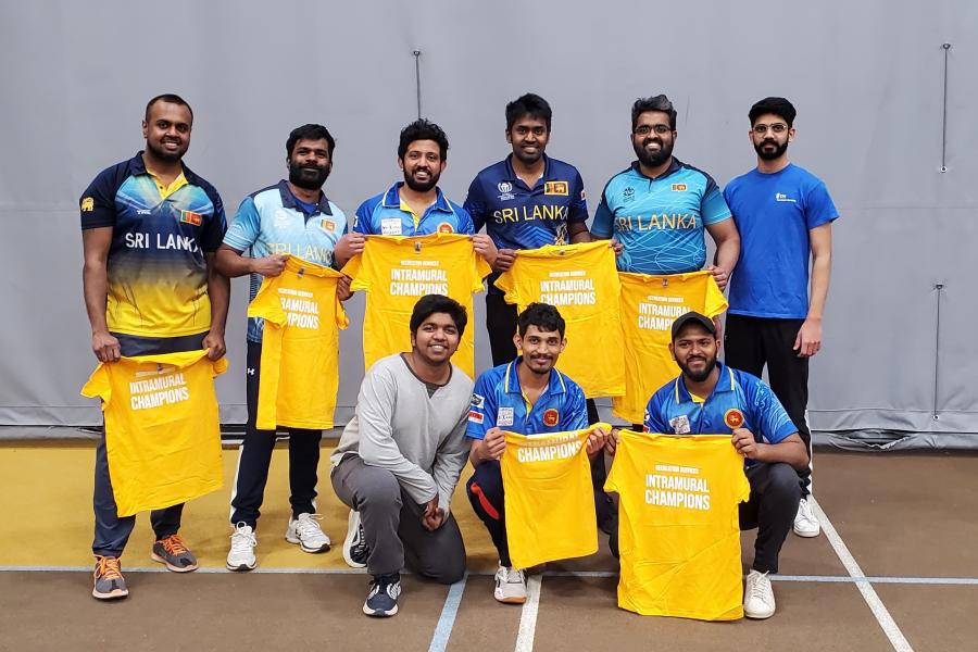 A team of cricket players hold up their championship t-shirts after a match