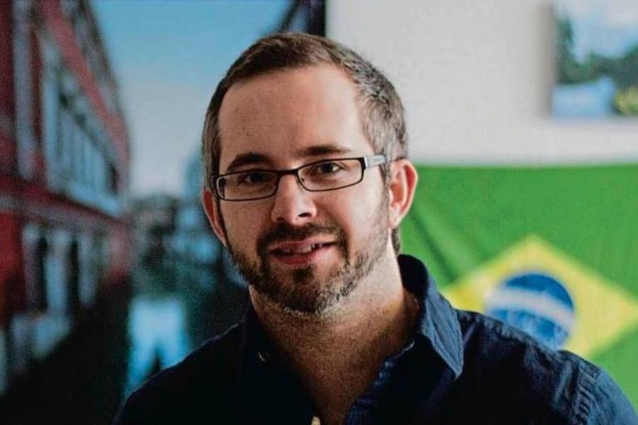 Kelly Hiebert standing in front of a Brazilian flag.