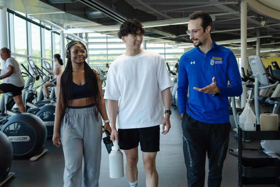 A young man and woman walk with a recreation services staff member through the active living centre