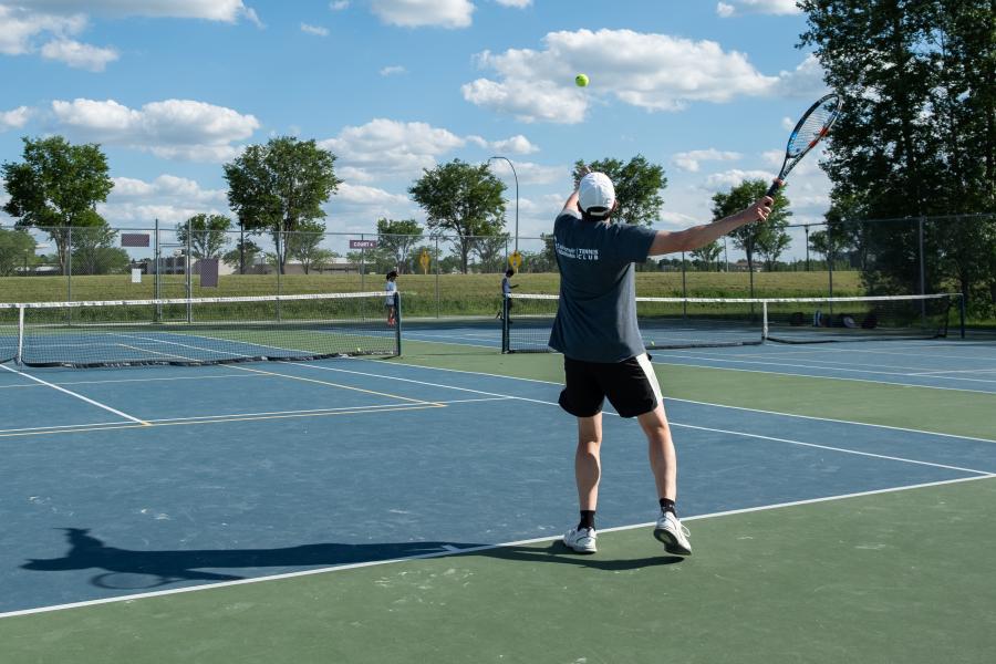 A tennis player throws the ball in the air to serve