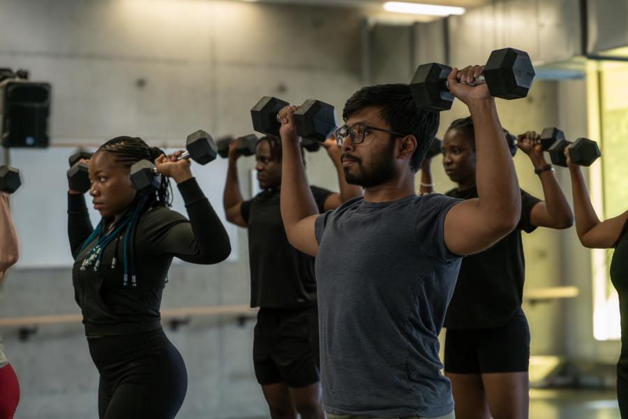 A young man lifting weights during a group fitness class