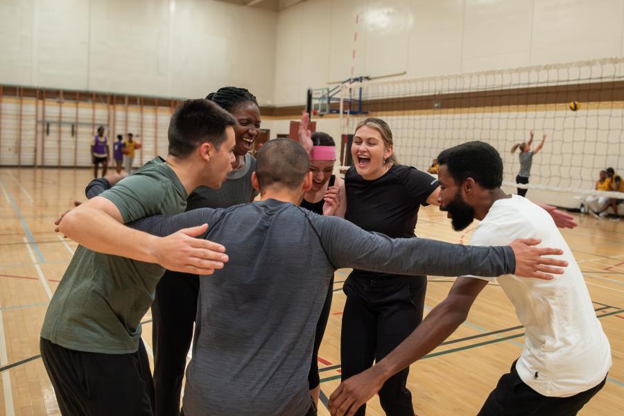 A group of people coming together to celebrate during a game of volleyball