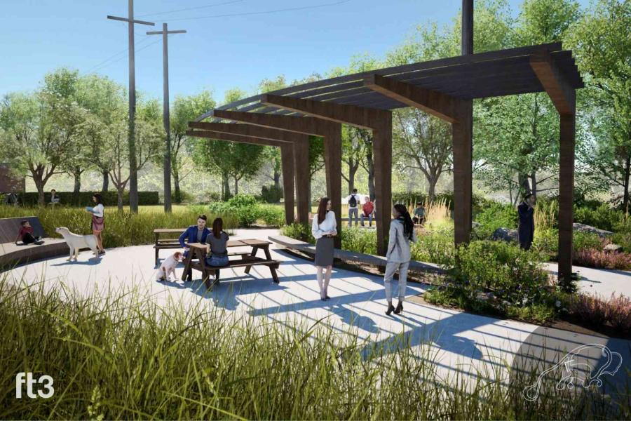 People standing and sitting under a shade structure with grasses, shrubs and trees.