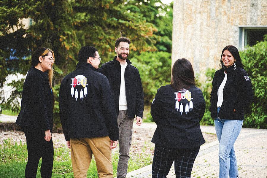 A group of students outdoors on campus exchanging ideas.