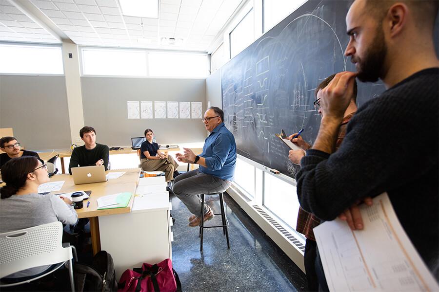 A professor and students in a classroom with a blackboard.