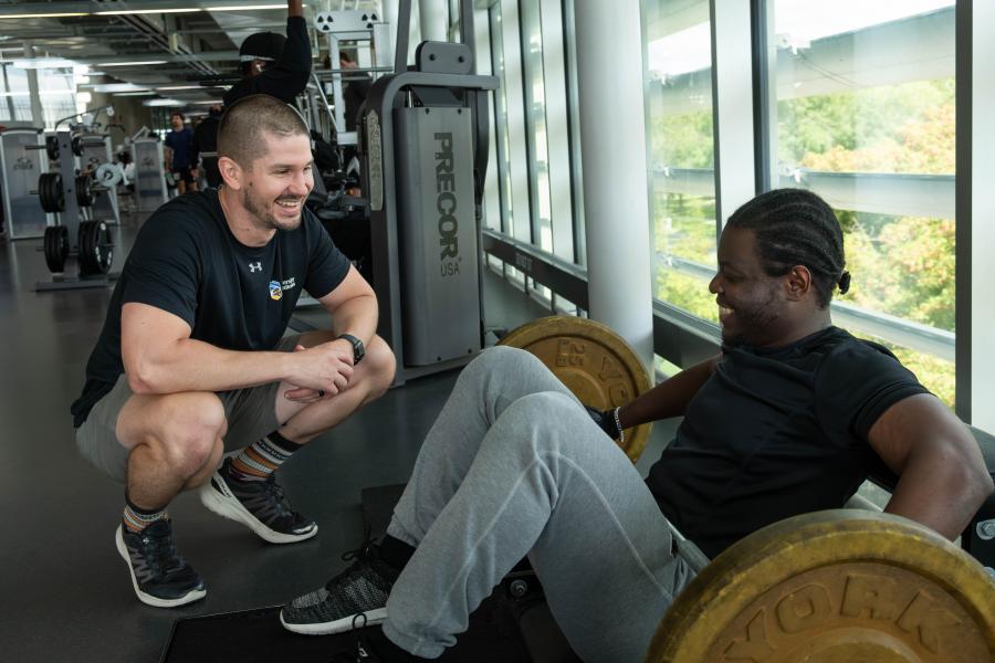 A personal trainer speaking with a client during an exercise