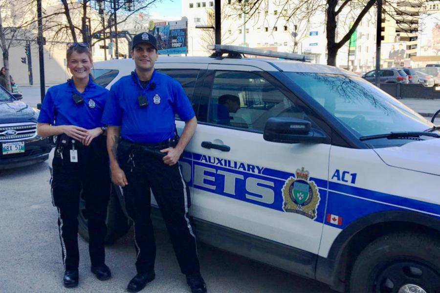 Two police cadets standing beside a vehicle