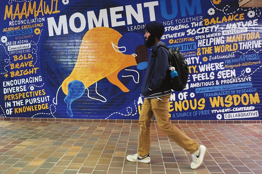 A student walks past a mural with a painted bison and the word momentum. 