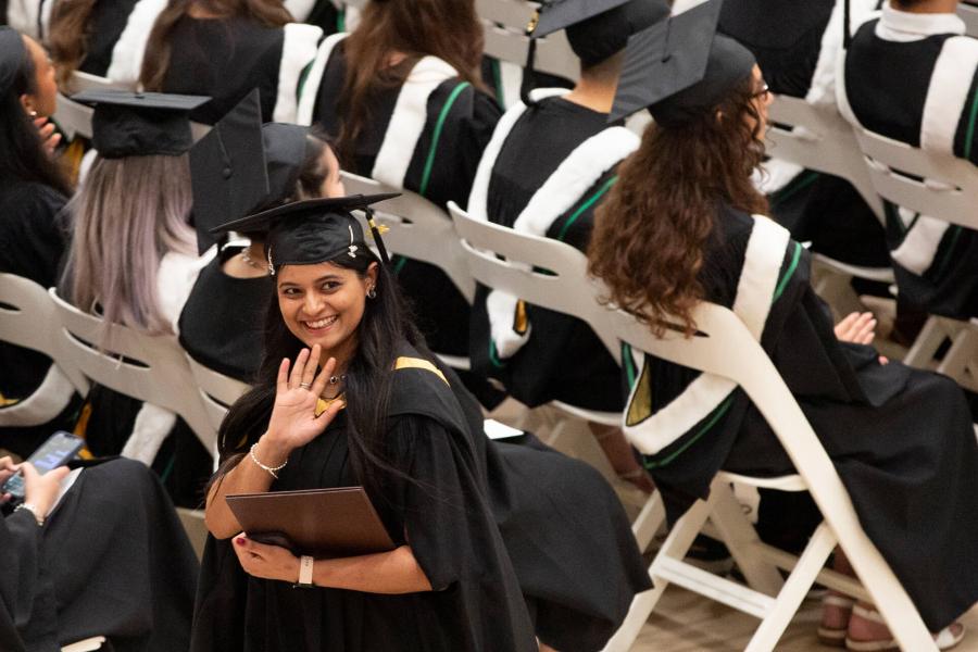 A student waves to supporters during a convocation ceremony.