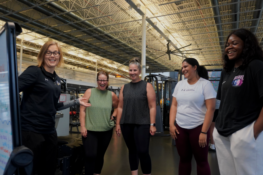 A group of women standing together listening to a personal trainer