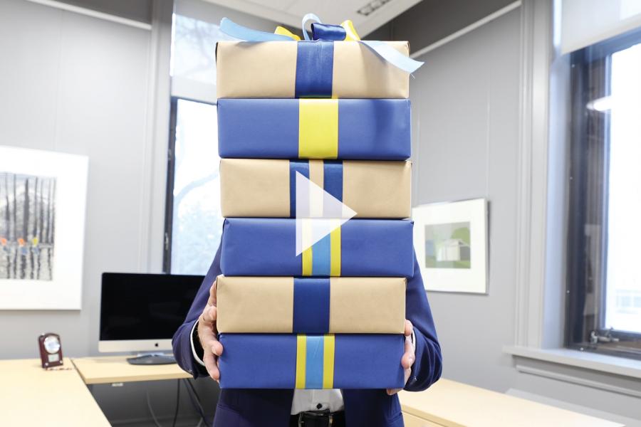 President Michael Benarroch holding stack of holiday gifts