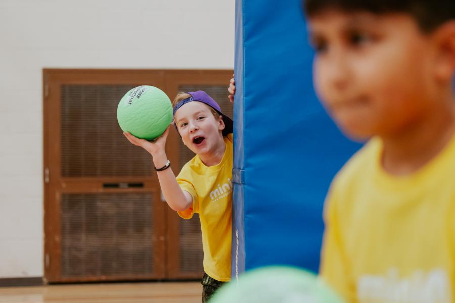 Child throwing dodgeball in a yellow shirt