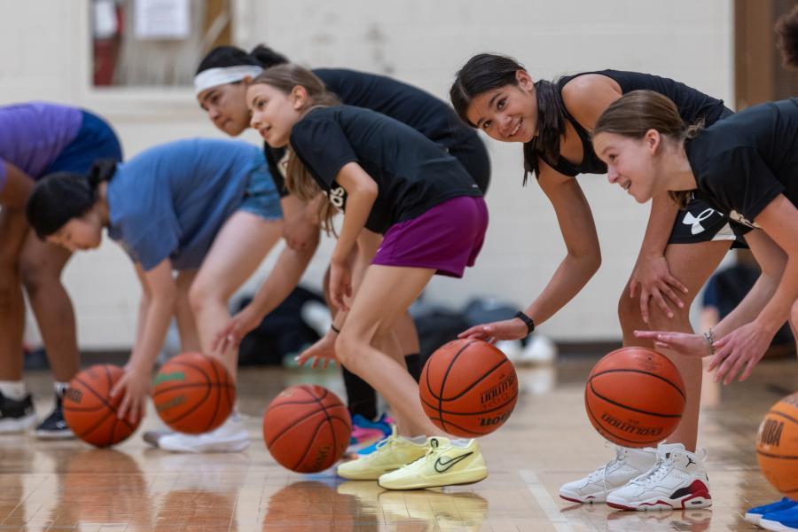 A group of campers bouncing basketballs in a line