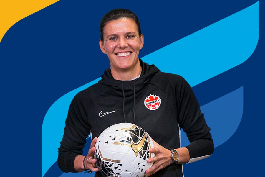 Christine Sinclair smiling and holding a soccer ball, in front of a UM branded background. 