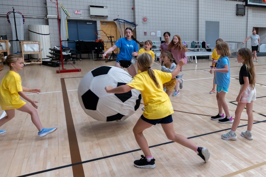 A Mini U leader playing giant soccer with a group of campers