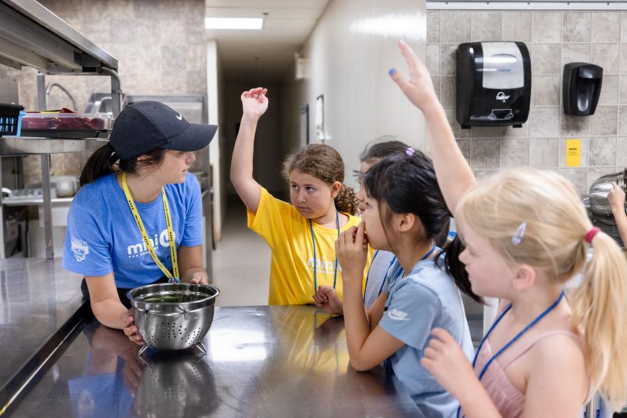 A mini u staff member inviting questions from campers during a kitchen activity