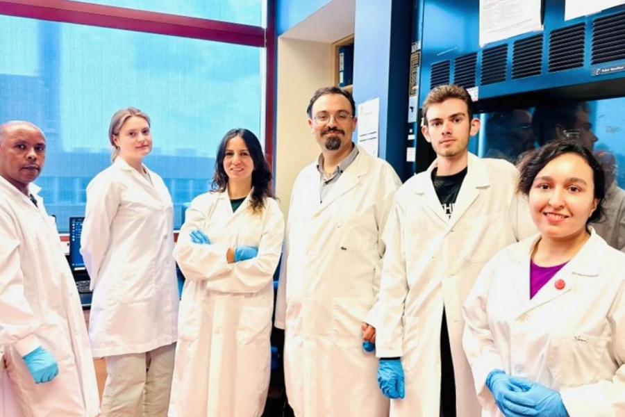 Five members of the Zovalis Research Team pose for a picture in a lab wearing their lab coats.
