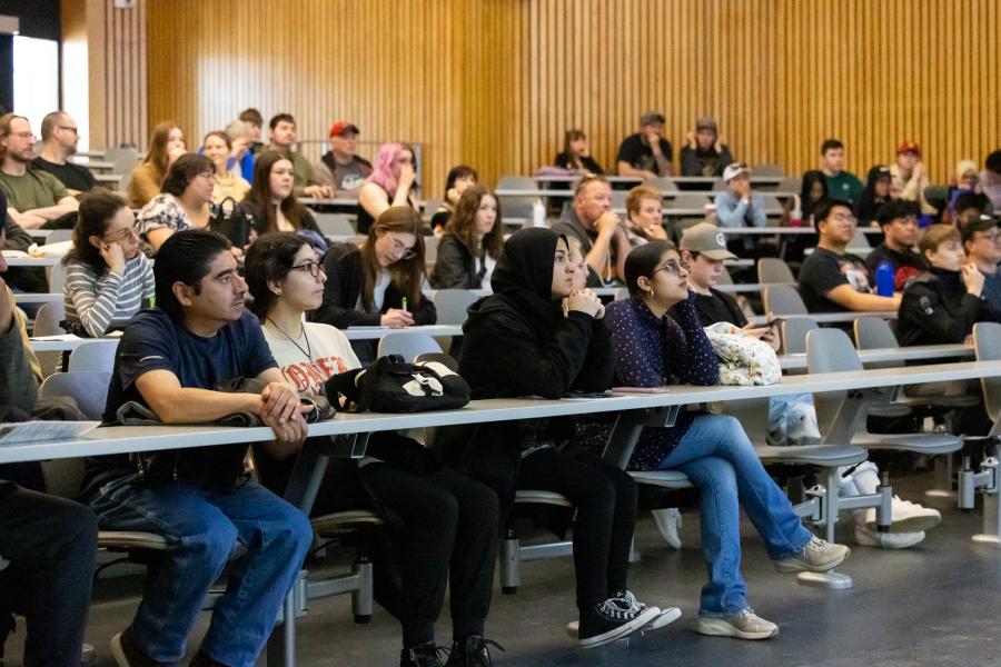 5 rows of students looking toward the front of the classroom in a large lecture hall.