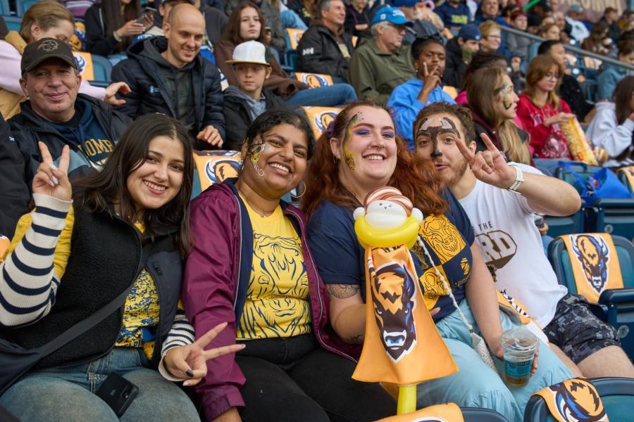 Four people posing at a homecoming game in their Bisons gear.