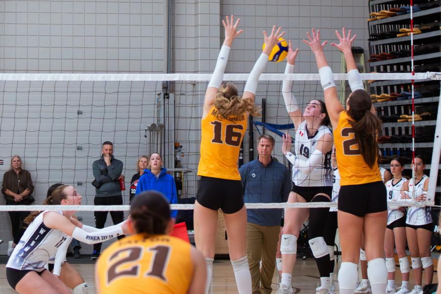 Junior Bisons volleyball players block a play from the opposing team.