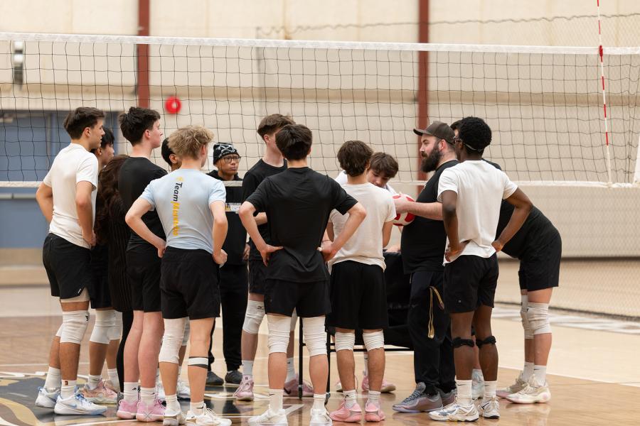 A Junior Bisons boys team huddles around the coach during a volleyball practice.