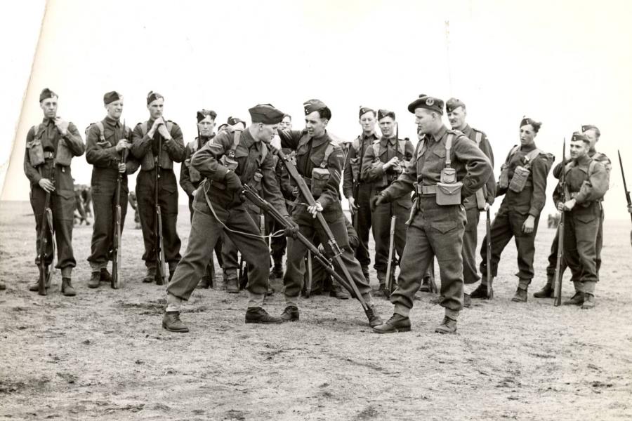 Soldiers in military uniforms practicing bayonet exercises in an open field.