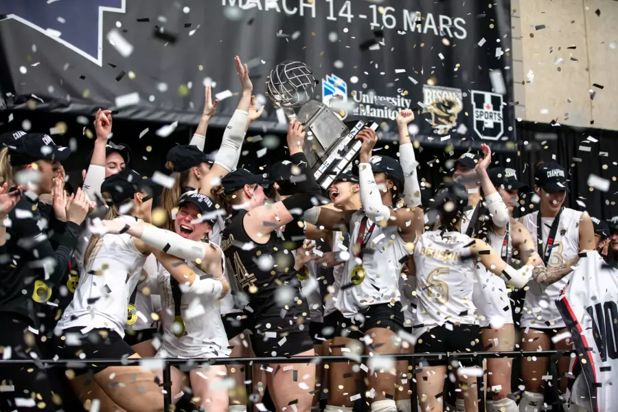 The women's volleyball team celebrate their national championship win on stage.