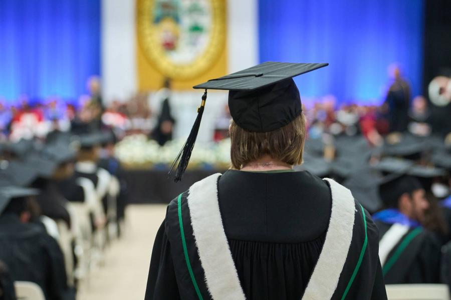 A student stands at convocation ceremonies with their back to the camera