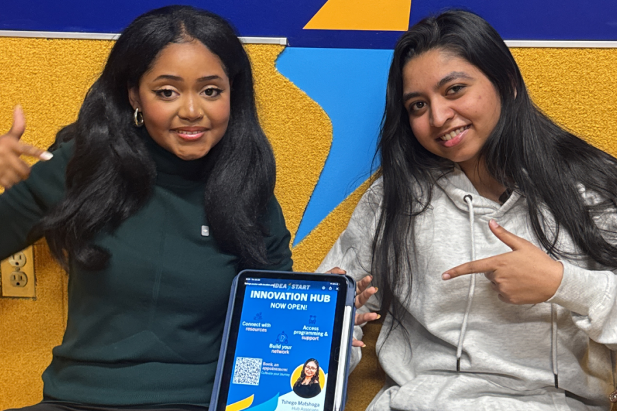 Two people smiling in University Centre with an IDEA START Innovation Hubs sign.
