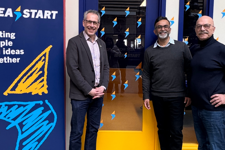 Three men standing beside an IDEA START sign and branded entrance.